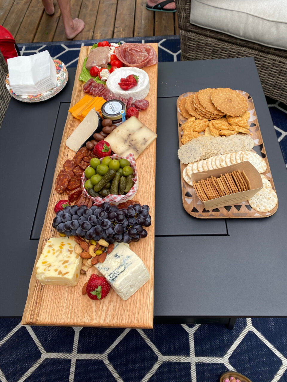 Long wooden board with charcuterie items such as meat, cheese, fruit, crackers etc.