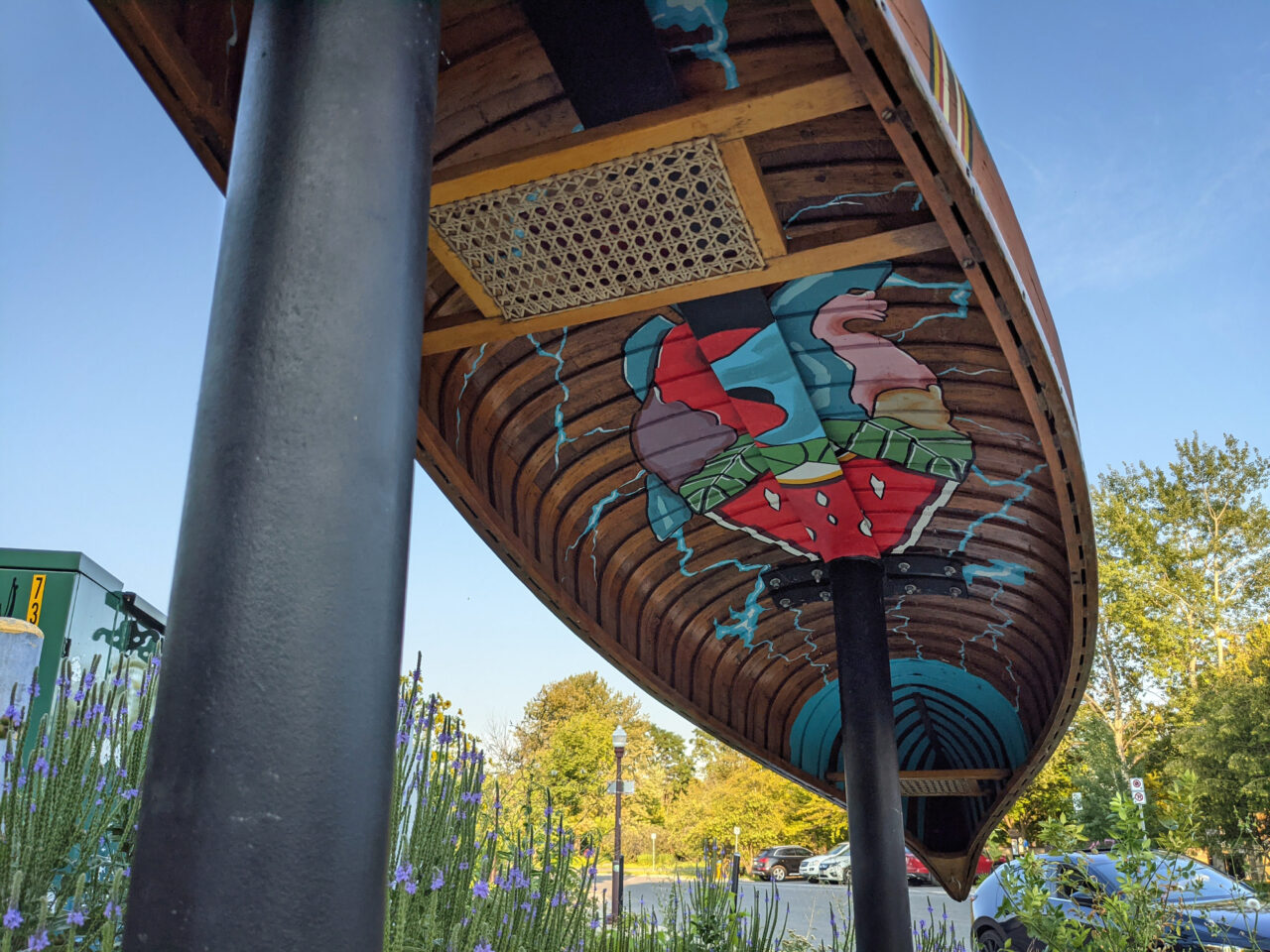 image of the underside of a canoe mounted upside down. Indigenous art painted inside the canoe.
