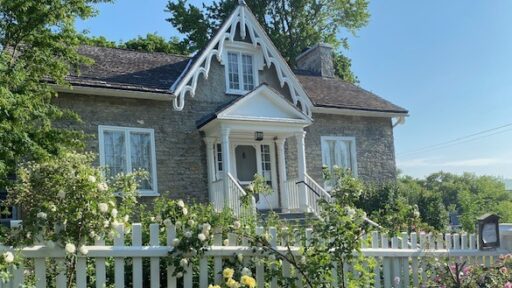 Hutchison House Museum in Peterborough Ontario - limestone cottage with white picket fence with flowers in full bloom.