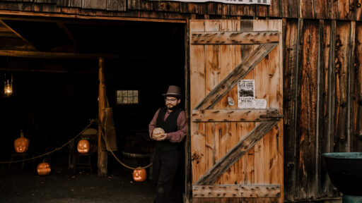 Man stands at the doorway of Blacksmith shop decorated for Halloween.