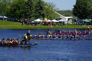 people in large row boats, rowing for an event in a lake