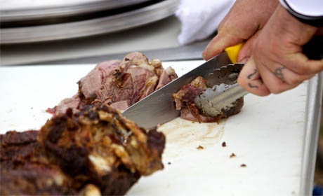 a chef cutting ribs on a cutting board with a knife