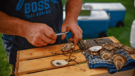 a person holding a knife shucking oysters