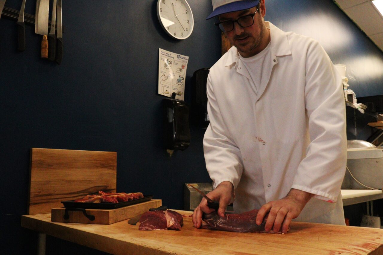 Butcher cutting meat on wooden chopping block