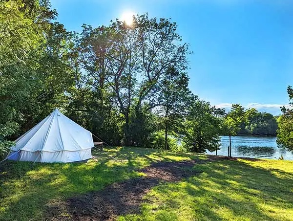 White prospector style tent in nature looking towards river.