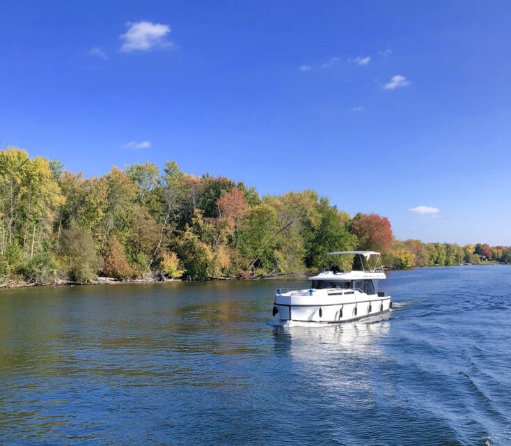 Le Boat cruising along the Trent-Severn Waterway. Peaks of fall foliage in the background.