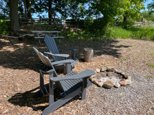 Two chairs beside a camp fire in the woods