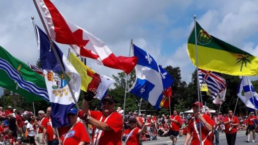 an image of people walking with flags, dressed in red for a Canada Day celebration