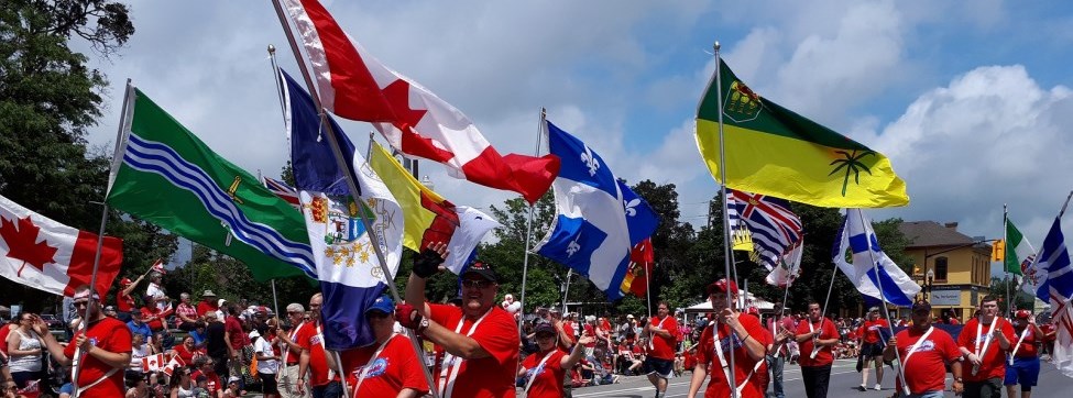 an image of people walking with flags, dressed in red for a Canada Day celebration