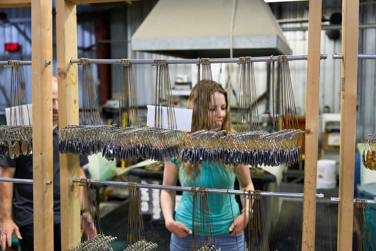 a woman looking at a rack of fishing spoons