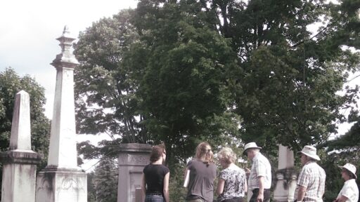a group of people in front of a tombstone in a cemetery