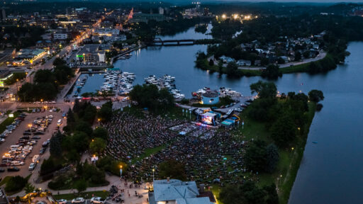 Aerial photograph of Peterborough Musicfest, with concert crowd in the foreground and marina, lakes and city in the background.