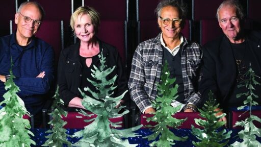 4 people standing with christmas decorations around them