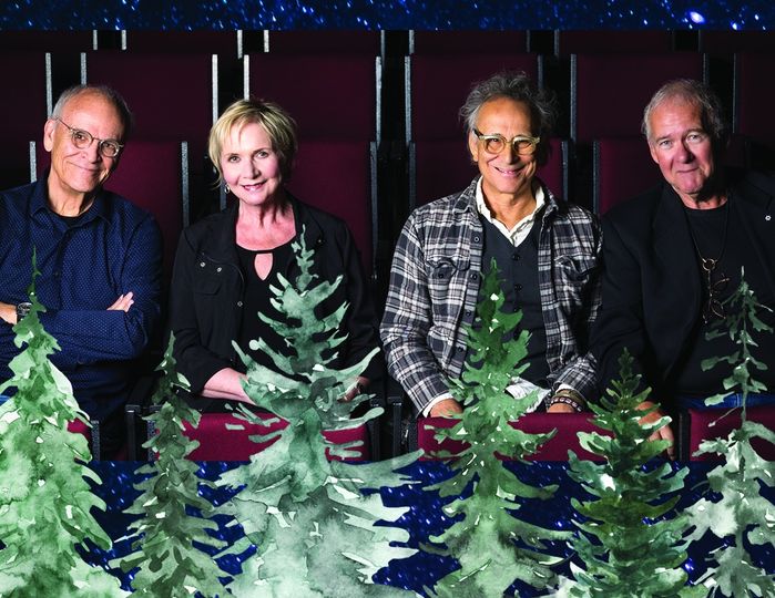 4 people standing with christmas decorations around them