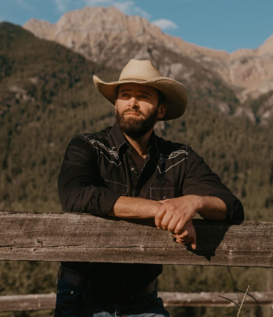 man with a cowboy hat with a background of mountains