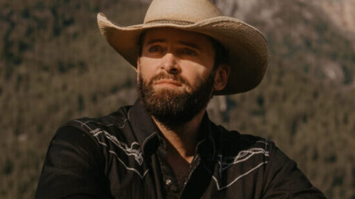 man with a cowboy hat with a background of mountains