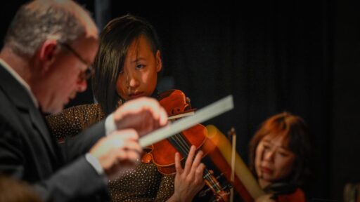 two woman playing the violin and a composer