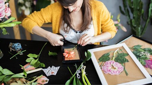 woman pressing flowers into a picture frame