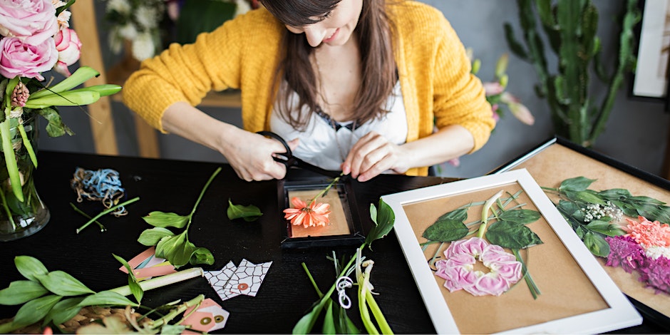 woman pressing flowers into a picture frame