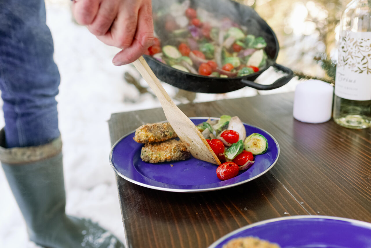 Hand platting food from cast iron pan outside in winter