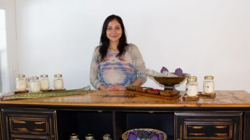 Owner of Indigenously Infused standing behind table with candle products on it