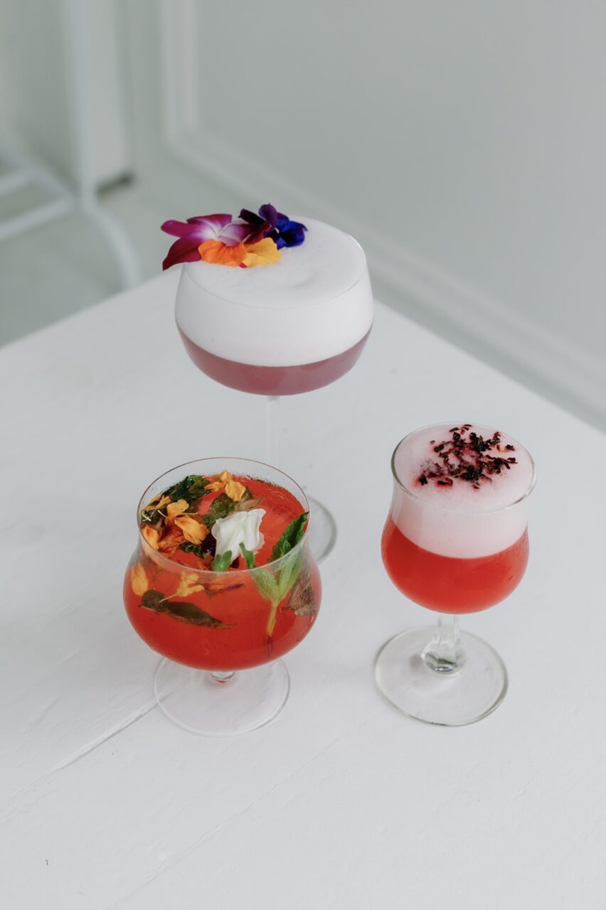 Three glasses with various pink cocktails