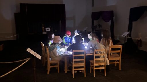 children sitting at a table in the dark