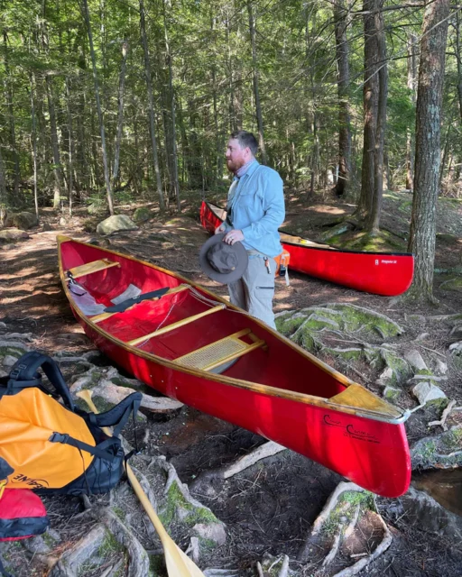 man with two canoes and backpacking gear