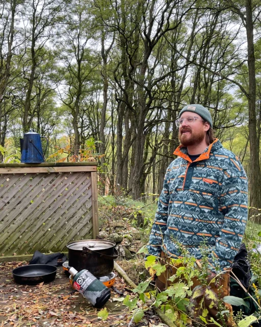 man in woods with cooking materials