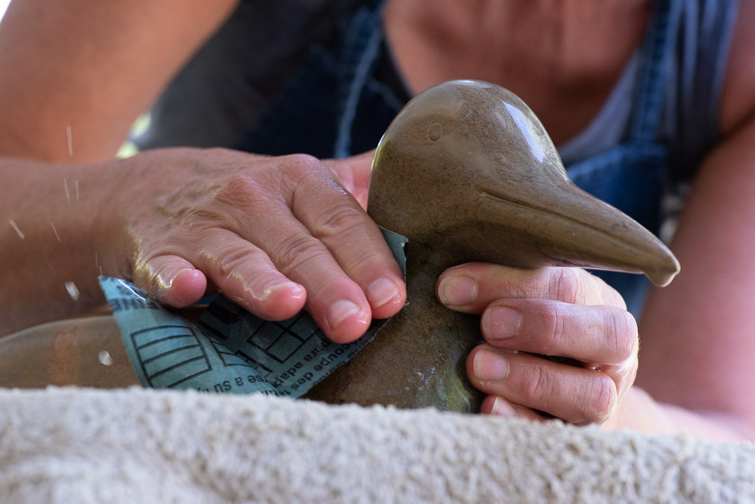 Hands shining a sculpture of a duck