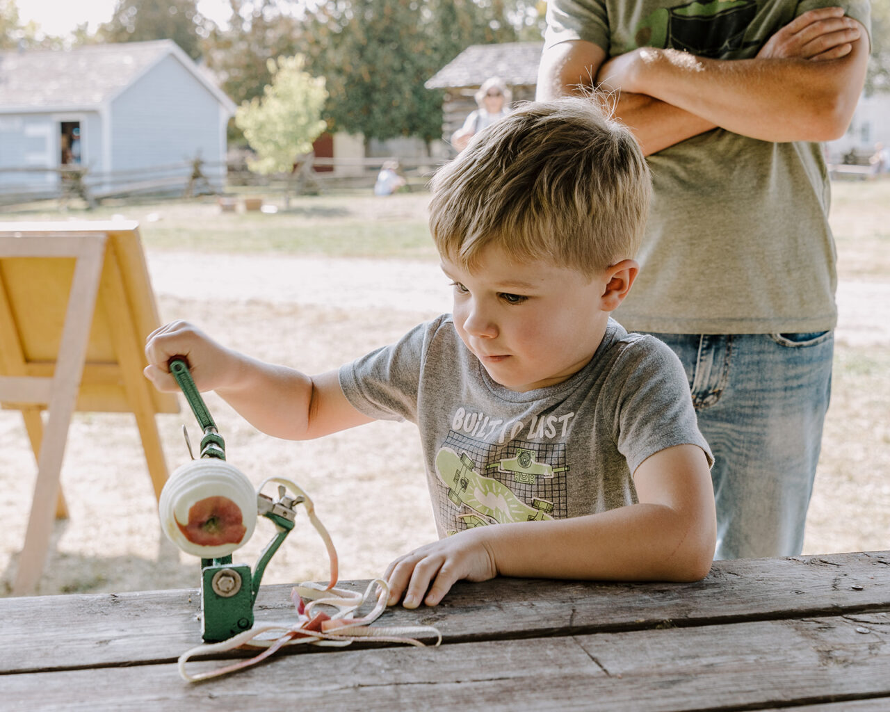 little boy using an apple peeling machine