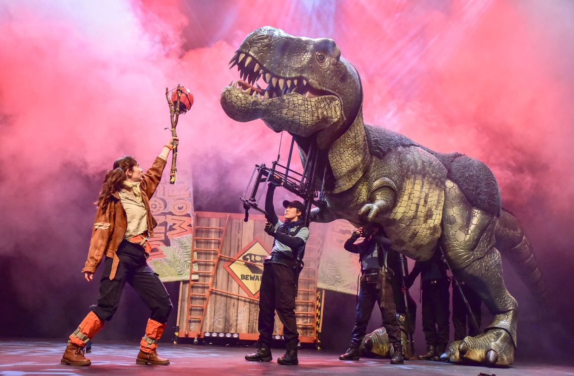 animatronic dinosaur controlled by a woman and another woman feeding it an apple