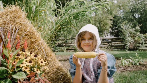 girl smiling holding corn