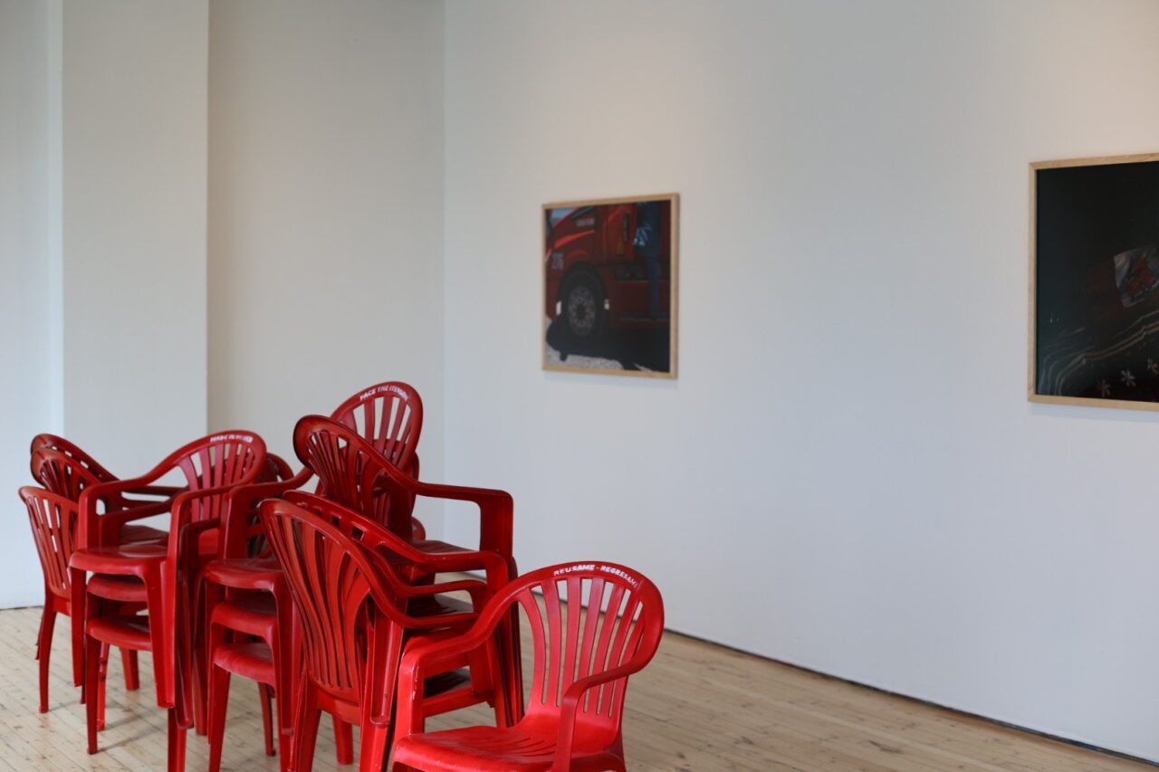 two pieces of artwork and stacked red chairs