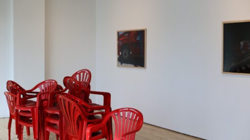 two pieces of artwork and stacked red chairs