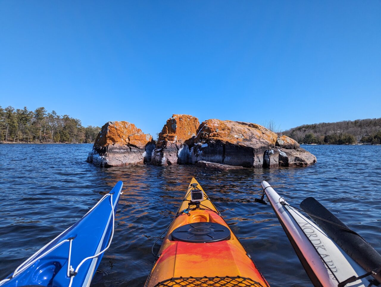 3 kayaks in water looking towards rocks popping out of the water