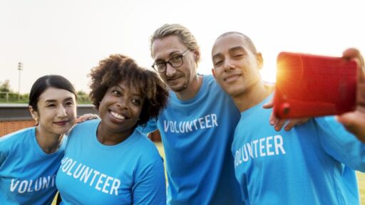 four people wearing volunteer shirts taking a selfie