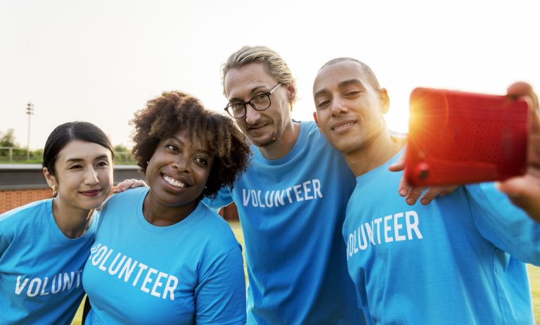 four people wearing volunteer shirts taking a selfie