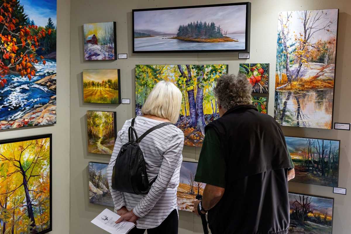 two people looking at paintings