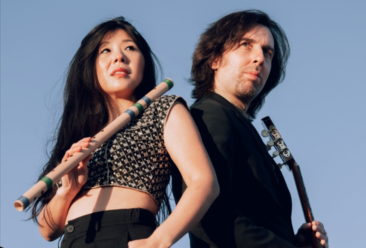 woman and man posed with a guitar and wind instrument